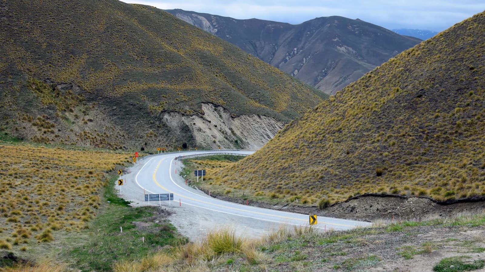 Winding highway through tussock-covered high country hills in New Zealand