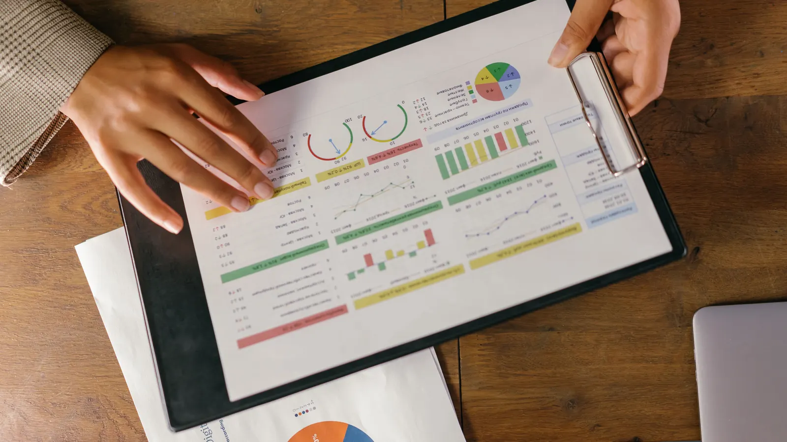 Hands holding a clipboard with a printed financial report full of charts and graphs