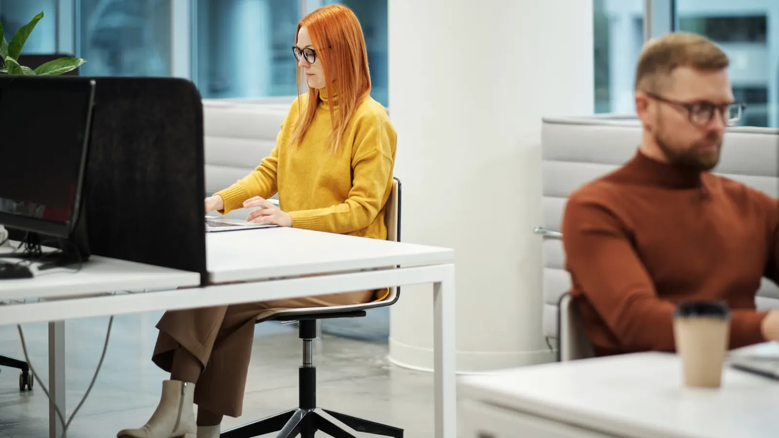 Office worker using a laptop in a modern open-plan workspace