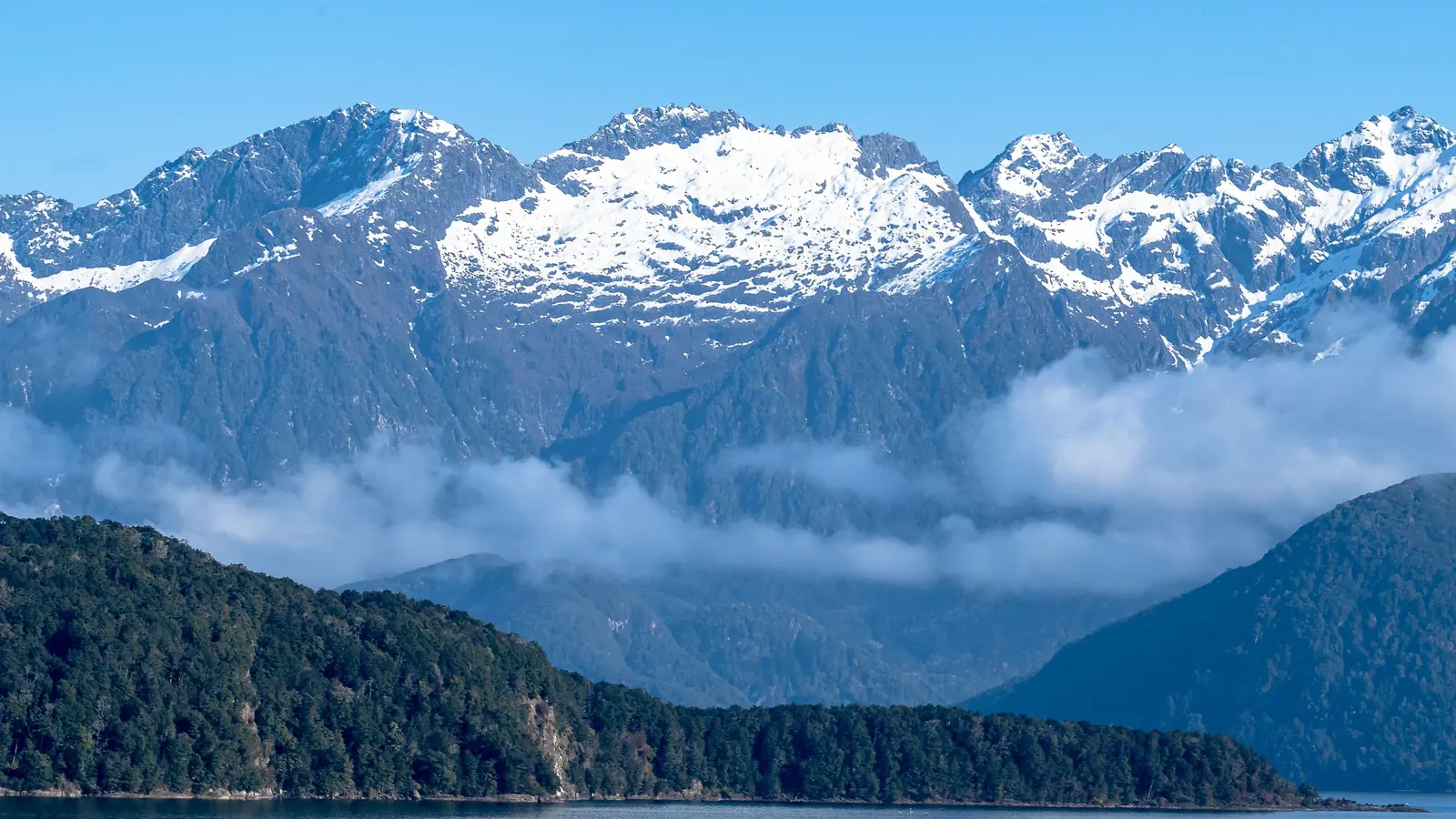 Layered mountain ranges and cloud above a New Zealand fiord