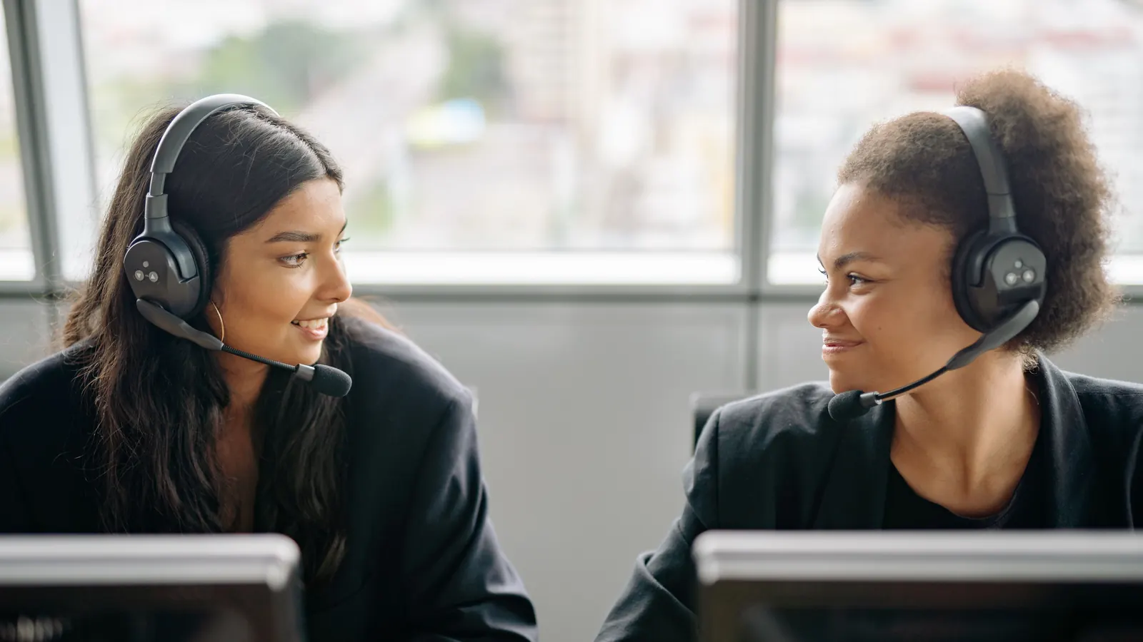 Two accounts staff wearing headsets at their monitors in an office
