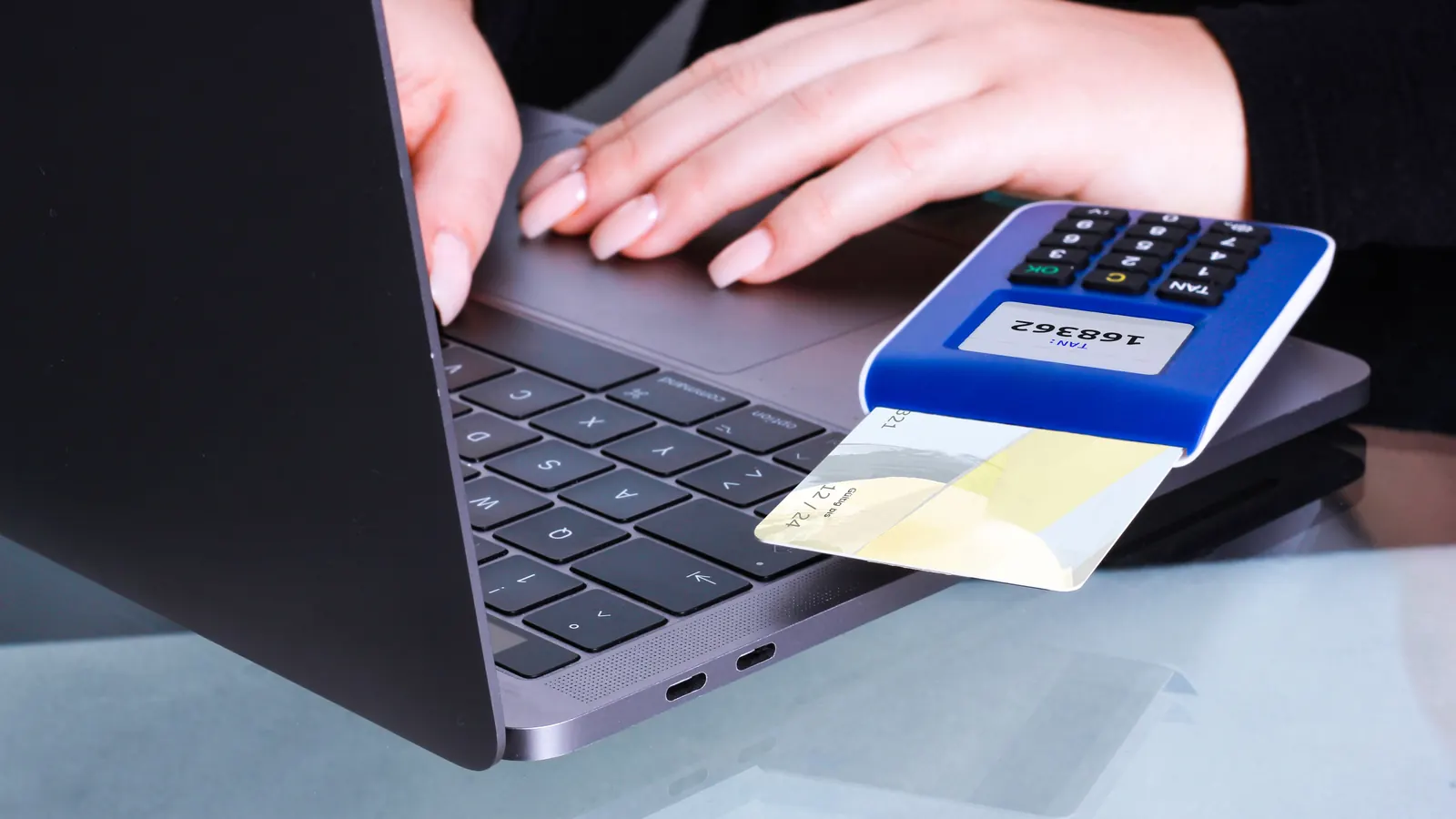A card being inserted into a payment terminal beside a laptop