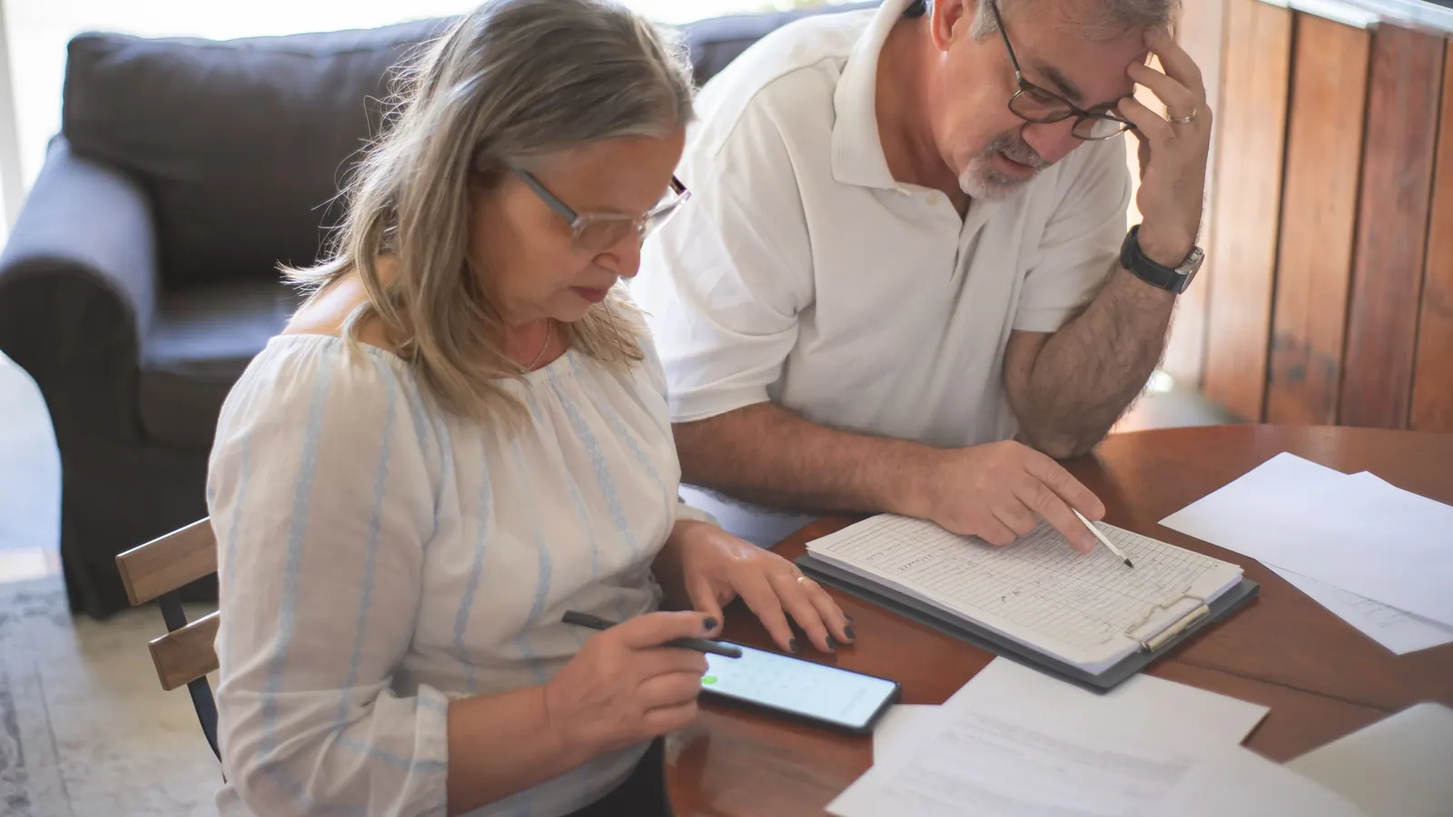 A couple reviewing bills and paperwork together at a home dining table